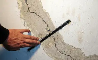 A wall with a large crack is being inspected by a professional in Fort Lauderdale, FL
